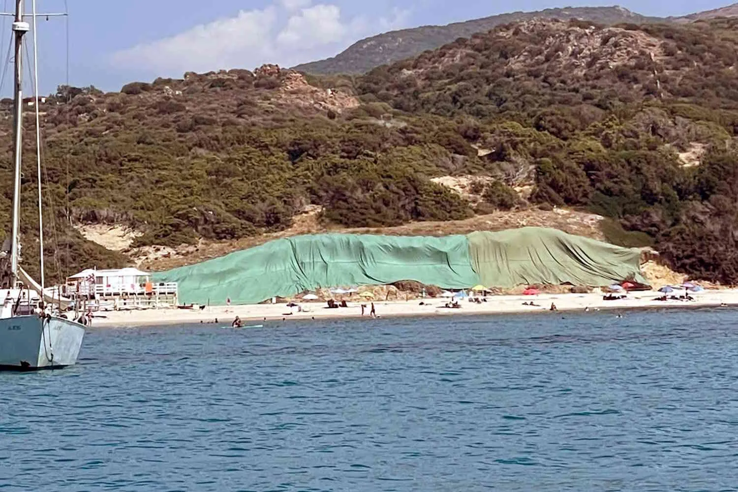Una vecchia discarica abusiva emerge da una spiaggia della Sardegna e il comune la copre con maxi teli verdi